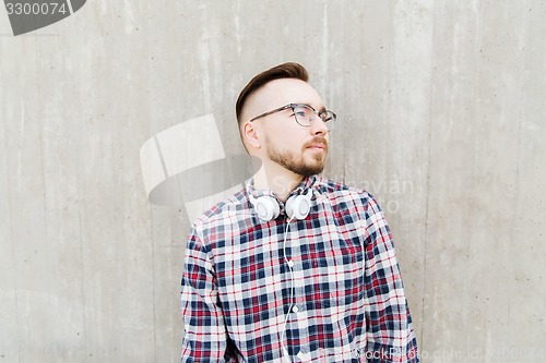 Image of happy young hipster man with headphones over wall