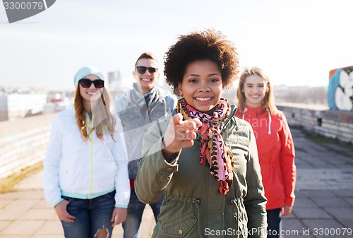 Image of happy friends pointing finger to you on street