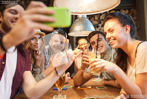 Image of happy friends with smartphone taking selfie at bar