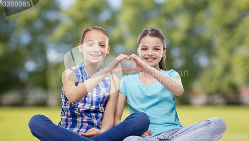 Image of happy little girls showing heart shape hand sign