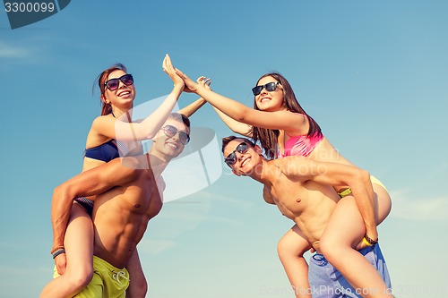 Image of smiling friends in sunglasses on summer beach