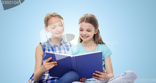 Image of two happy girls reading book over blue background