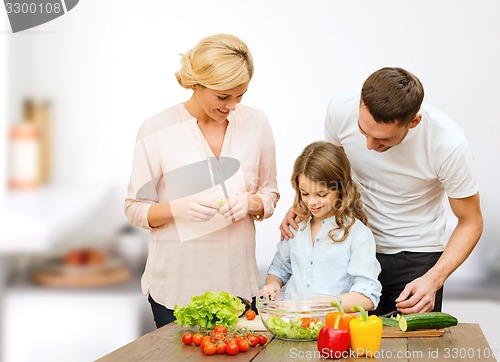 Image of happy family cooking vegetable salad for dinner