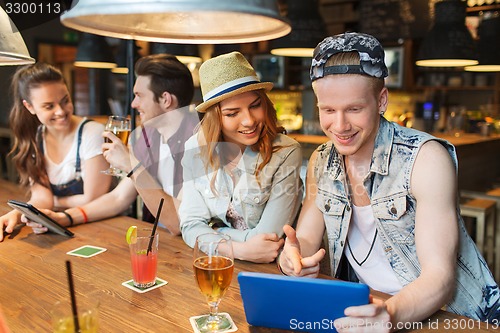 Image of happy friends with tablet pc and drinks at bar