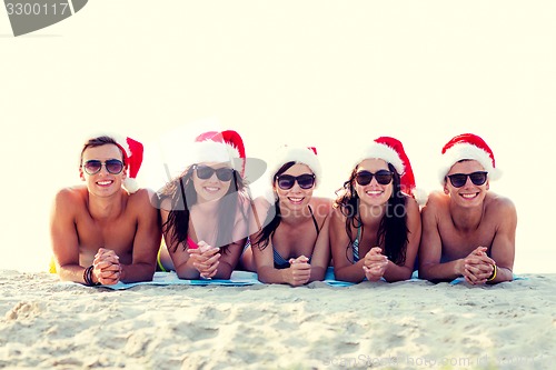 Image of group of friends in santa helper hats on beach
