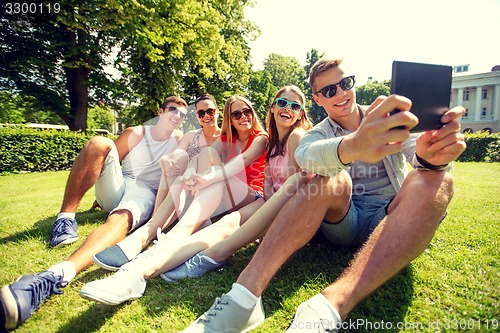Image of smiling friends with tablet pc computer in park