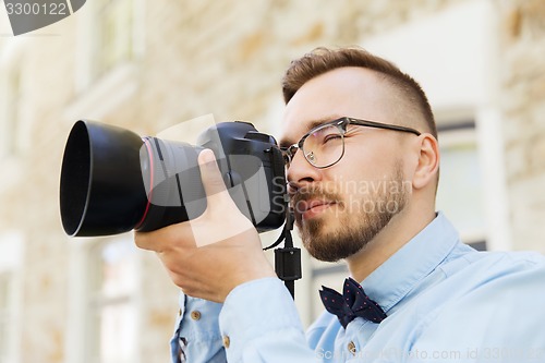 Image of young hipster man with digital camera in city