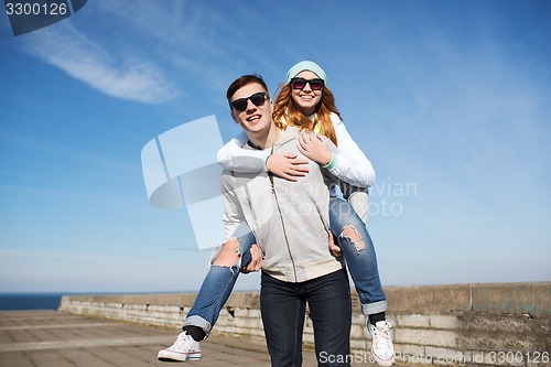 Image of happy teenage couple in shades having fun outdoors