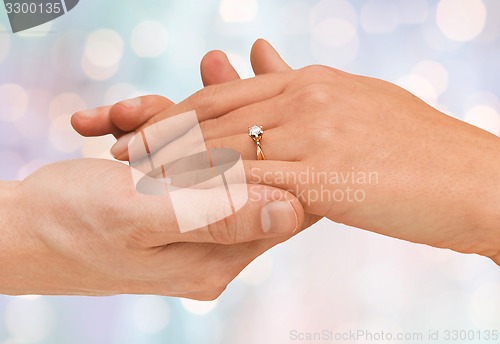 Image of close up of man and woman hands with wedding ring