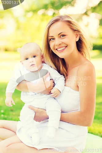 Image of happy mother with little baby sitting on blanket