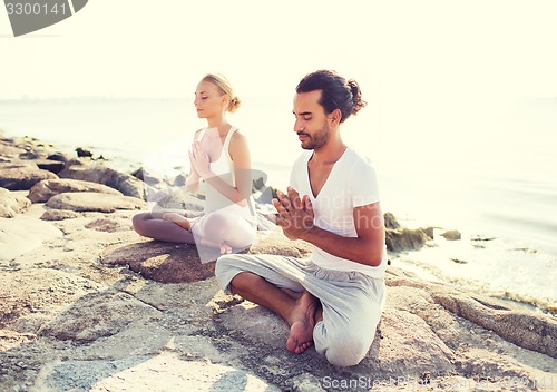 Image of smiling couple making yoga exercises outdoors