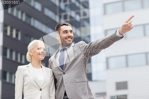 Image of smiling businessmen standing over office building