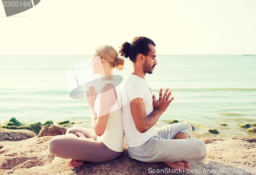 Image of smiling couple making yoga exercises outdoors