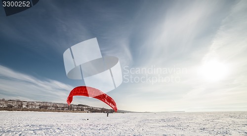 Image of Kiteboarder with blue kite on the snow