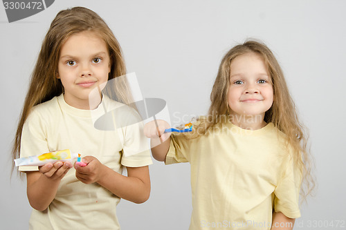 Image of The girl squeezes out a tube of toothpaste on the brush