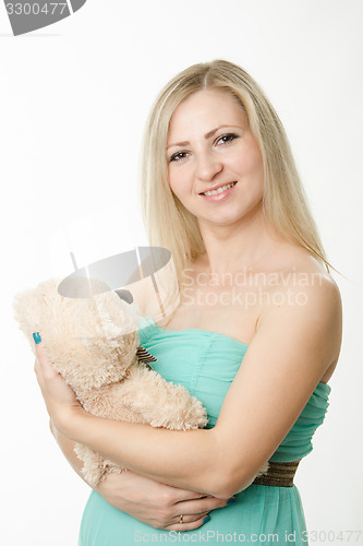 Image of The pregnant girl hugging a teddy bear