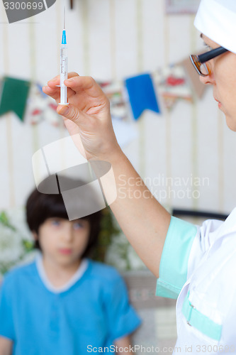 Image of Doctor pediatrician with a syringe and a child in the background