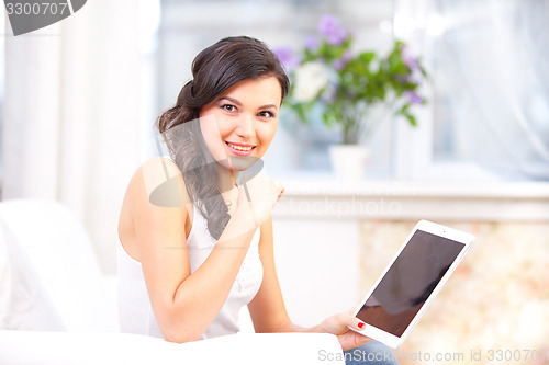 Image of smiling young girl reading  tablet