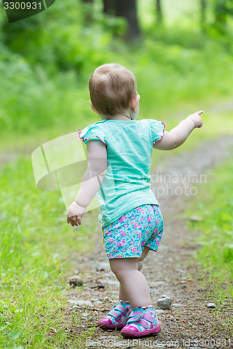 Image of Cute Little girl walking away on the road ahead