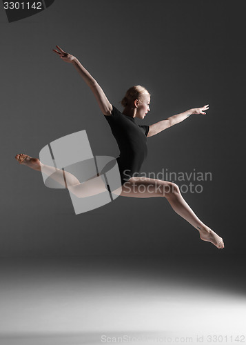 Image of Young beautiful modern style dancer jumping on a studio background