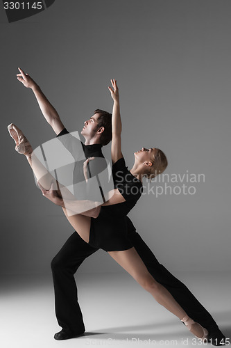 Image of two young modern ballet dancers on gray studio background 