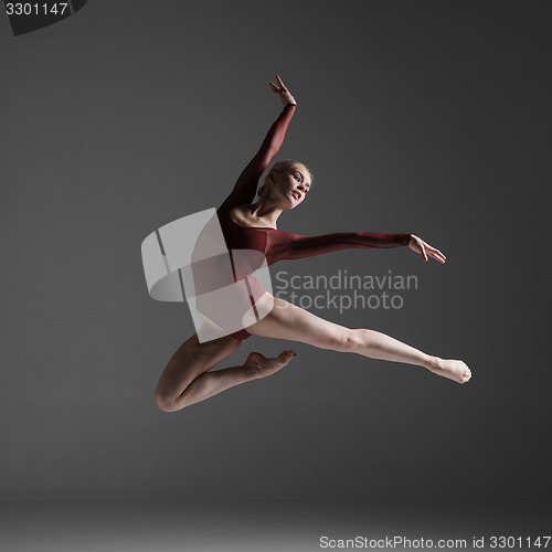 Image of Young beautiful modern style dancer jumping on a studio background