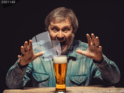 Image of The screaming man in denim shirt with glass of beer