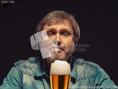 Image of The spellbound man in denim shirt with glass of beer