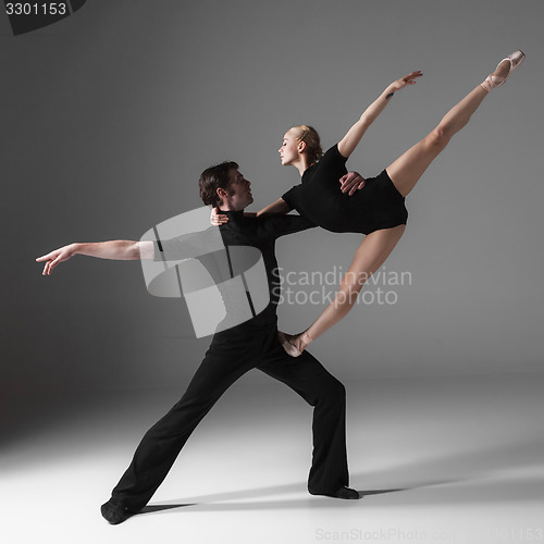 Image of two young modern ballet dancers on gray studio background 