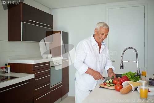 Image of man cooking at home preparing salad in kitchen