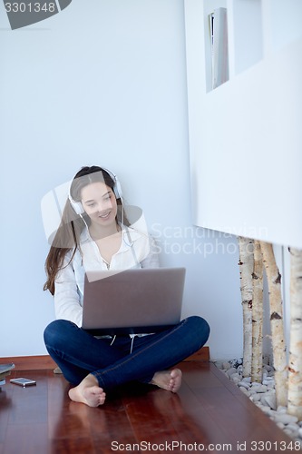 Image of relaxed young woman at home working on laptop computer