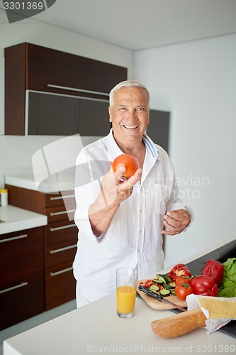 Image of man cooking at home preparing salad in kitchen