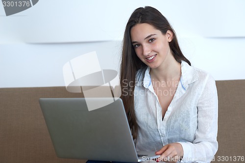 Image of relaxed young woman at home working on laptop computer