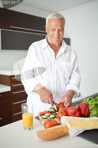 Image of man cooking at home preparing salad in kitchen