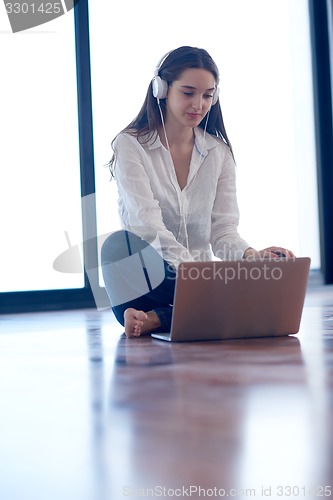 Image of relaxed young woman at home working on laptop computer