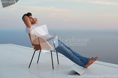 Image of relaxed young man at home on balcony