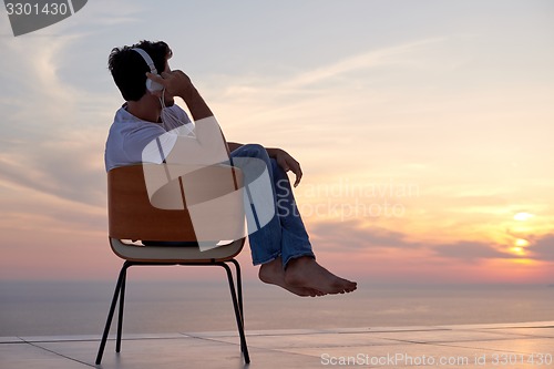 Image of relaxed young man at home on balcony
