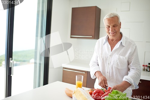 Image of man cooking at home preparing salad in kitchen