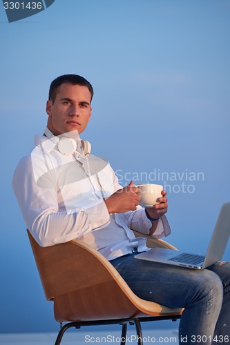 Image of relaxed young man at home on balcony