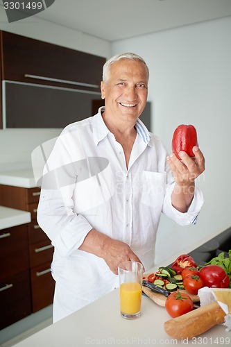 Image of man cooking at home preparing salad in kitchen