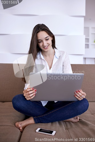 Image of relaxed young woman at home working on laptop computer