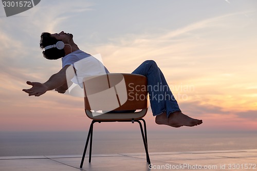 Image of relaxed young man at home on balcony
