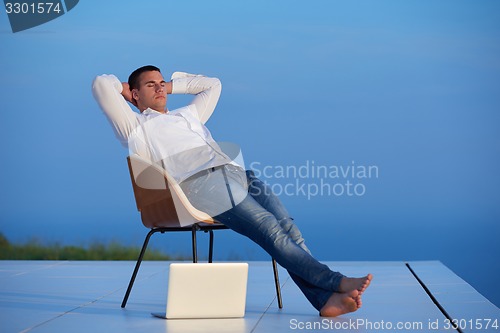 Image of relaxed young man at home on balcony
