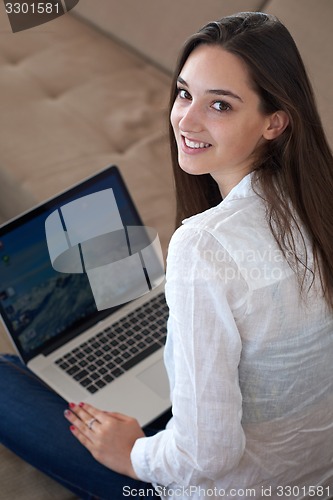 Image of relaxed young woman at home working on laptop computer