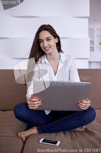 Image of relaxed young woman at home working on laptop computer