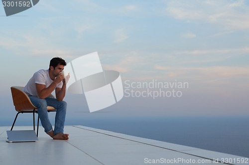 Image of relaxed young man at home on balcony