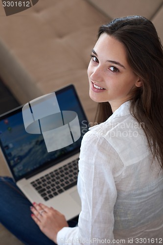 Image of relaxed young woman at home working on laptop computer
