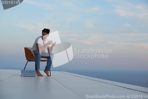Image of relaxed young man at home on balcony