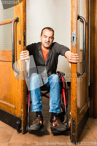 Image of Man in wheelchair stuck between swing doors