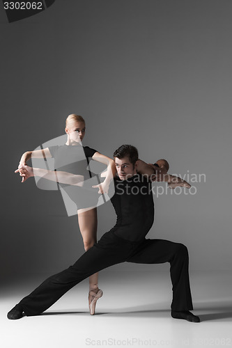 Image of two young modern ballet dancers on gray studio background 